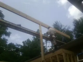 Carpenter setting a ridge beam over a new addition frame — Ice Dam Removal by Roofing Brothers in Leon