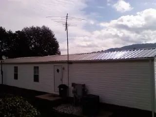 New metal roof on a single wide mobile home with a TV antenna in Leon