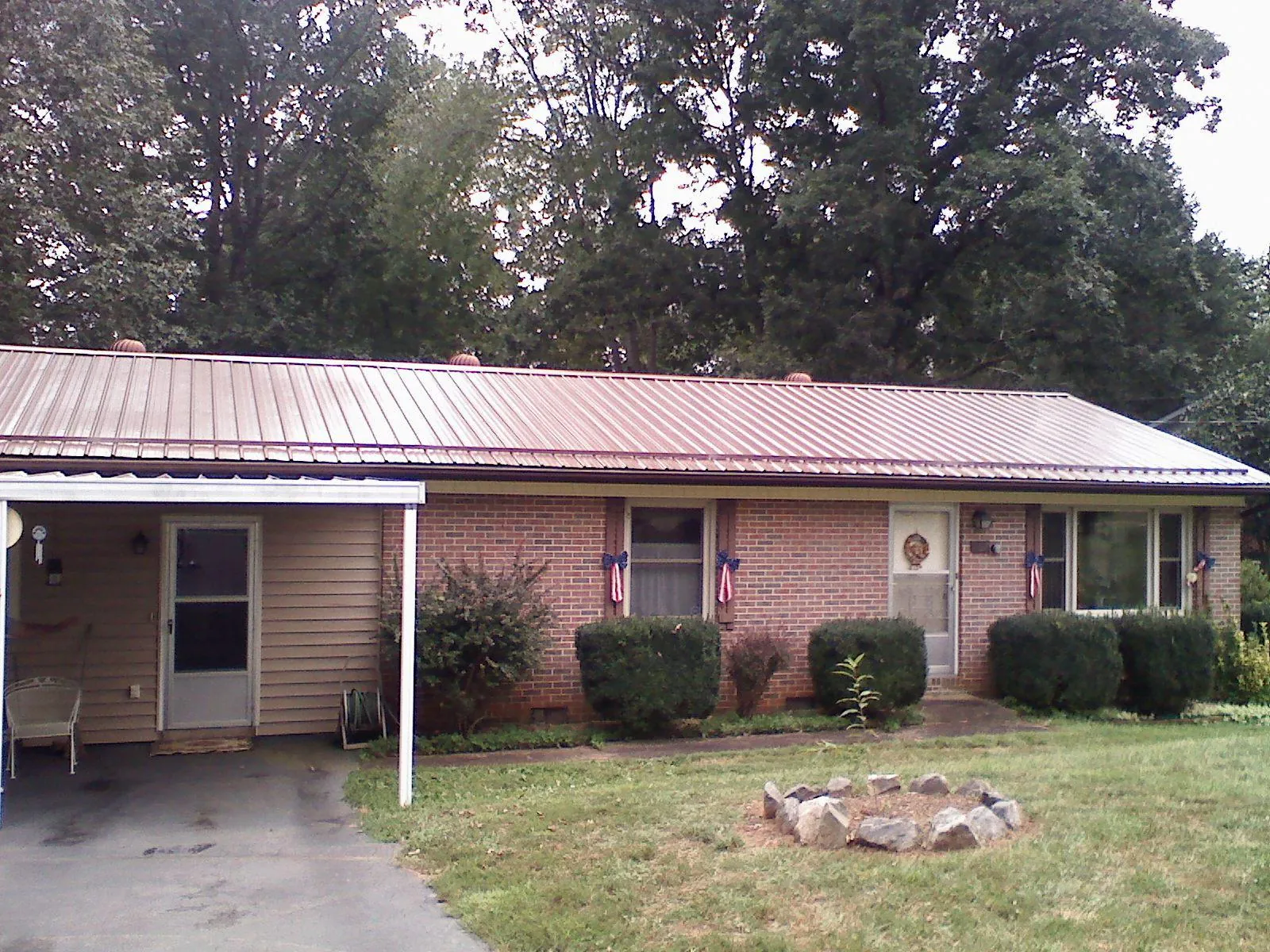Bronze metal roof and carport on a brick ranch home — Roof Repair work by our crew in Leon